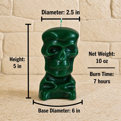 A dark green skull-shaped ritual candle is shown with technical measurements against a stone wall background. The candle is 5 inches in height, 2.5 inches in diameter at the top, and sits on a 6-inch base diameter. Text to the right indicates a net weight of 10 oz and a burn time of 7 hours. 